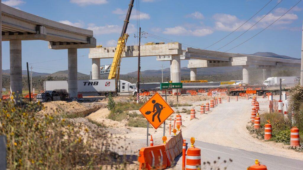 Construction Site on a Desert Highway with an Unfinished Elevated Roadway, Crane, and Orange Traffic Cones. - Regios En México